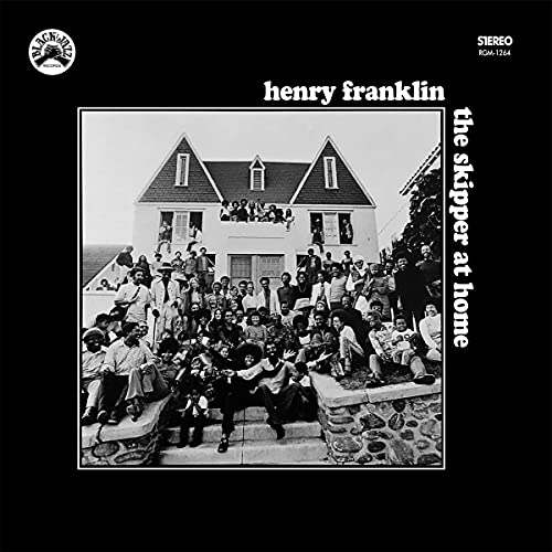 Black and white album cover featuring a large group in front of a house.