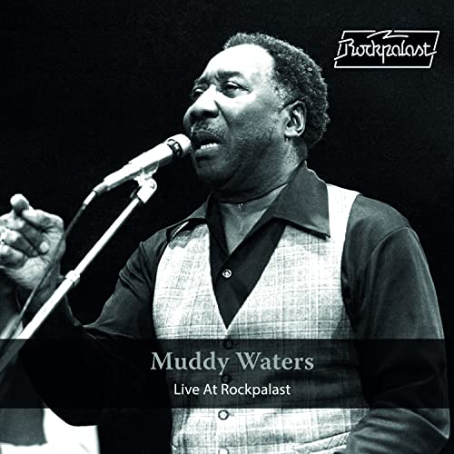 Black and white portrait of Muddy Waters singing into a microphone.
