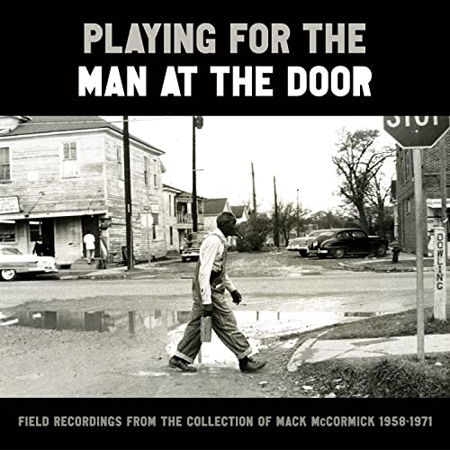 Vinyl album cover: black and white street scene with a walking man.