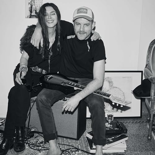 Black and white photo of two people with guitars and amplifier.