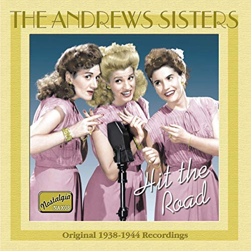 The Andrews Sisters in pink dresses pose with a vintage microphone.