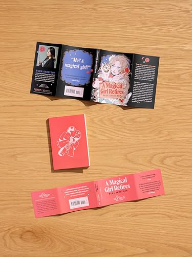 Open and closed paperback book, “A Magical Girl Retires,” on wood.