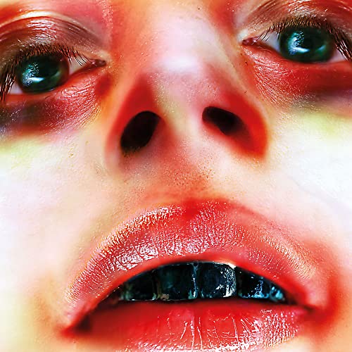 Close-up of a face with red tones and metallic teeth.