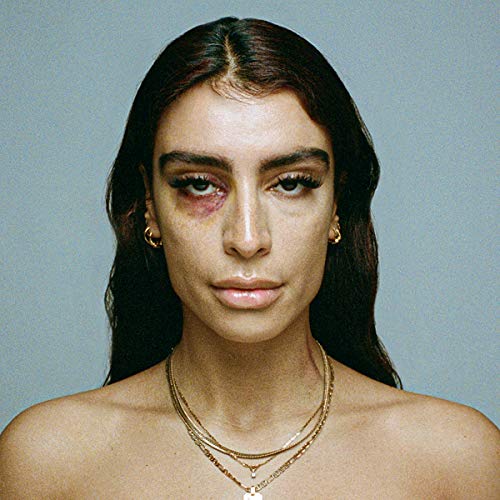 Close-up portrait of Sevdaliza with a bruise and layered gold necklaces.