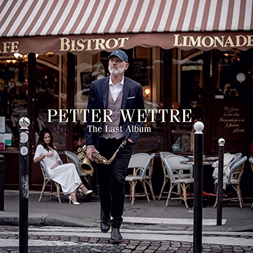 Man with saxophone stands outside a Parisian bistro, album cover.