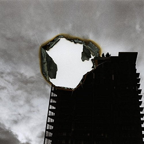Black and white image of a building with a circular hole in the sky.