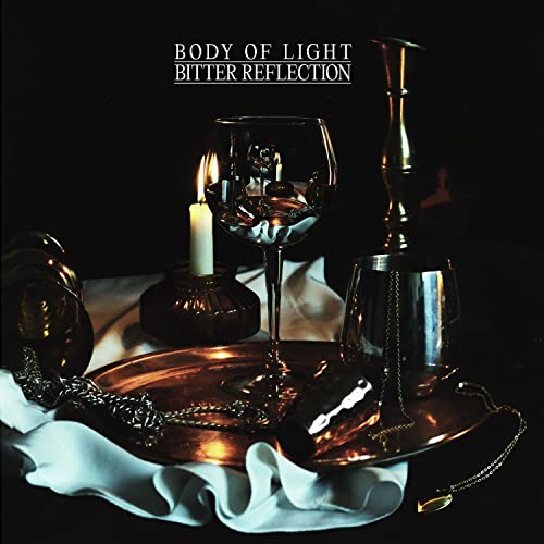 Dark still life with wine glass, candle, and metallic objects.