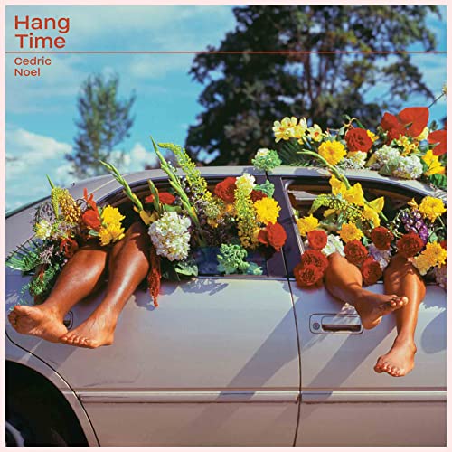 CD cover with legs dangling from a car covered in flowers.