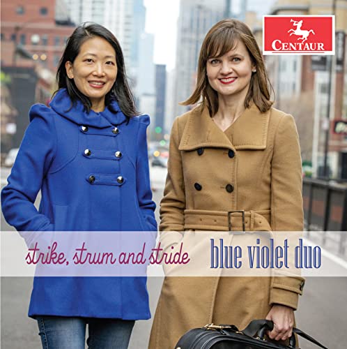 Two women stand on a city street, one in a blue coat, one tan.