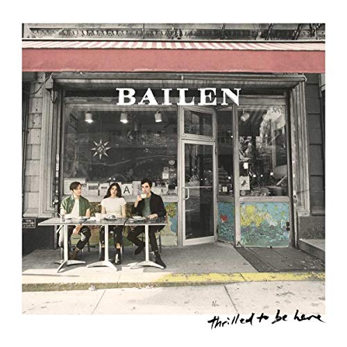 CD cover: three people seated at a table in front of a storefront.