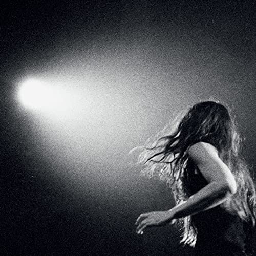 Black and white portrait of a woman with flowing hair, backlit.