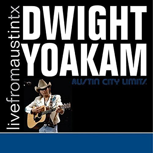Dwight Yoakam wearing a cowboy hat and playing acoustic guitar on a concert stage.