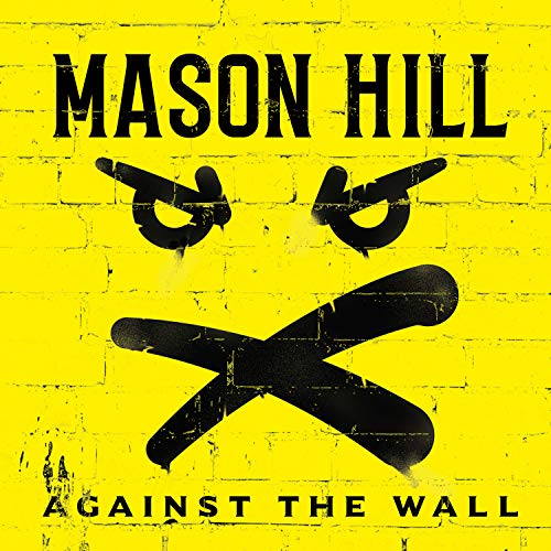 Yellow brick wall with black graffiti of a face and text.
