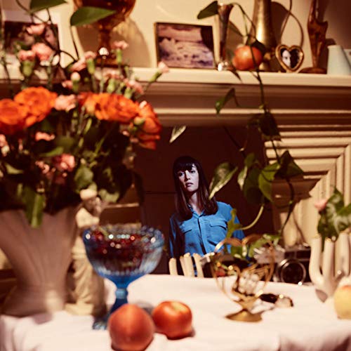 CD cover: woman in a mirror surrounded by flowers and objects.