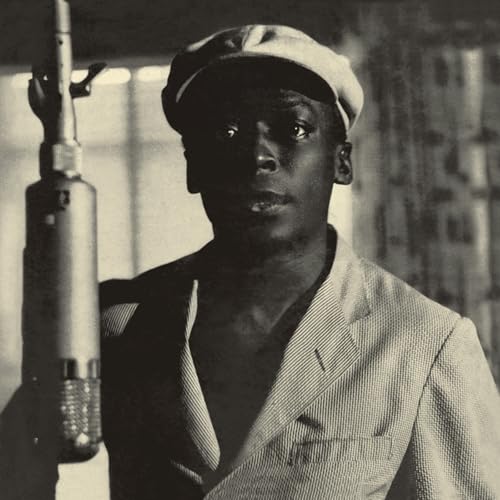 Black and white portrait of Miles Davis with a vintage microphone.