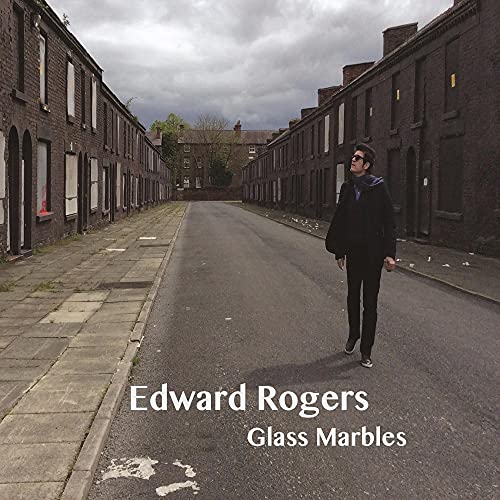 CD cover: Man walking down a street lined with brick houses.
