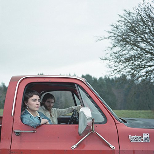 Woman and man in a red pickup truck, looking forward.
