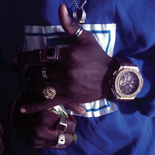 Dark-skinned hands with multiple rings and a gold watch, blue background.