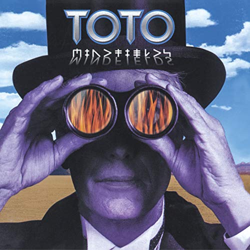 A man in a top hat looks through binoculars reflecting flames against a desert background.