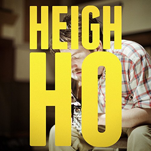 A man in a plaid shirt plays guitar behind large yellow text reading HEIGH HO.