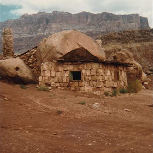 Stone hut with a window, set against a desert mountain backdrop.