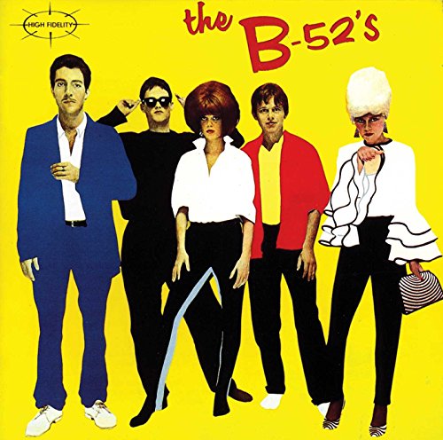 The five members of The B-52's stand against a bright yellow background.