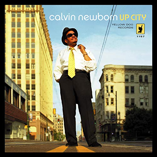 CD cover: Man in hat and suit stands on city street.