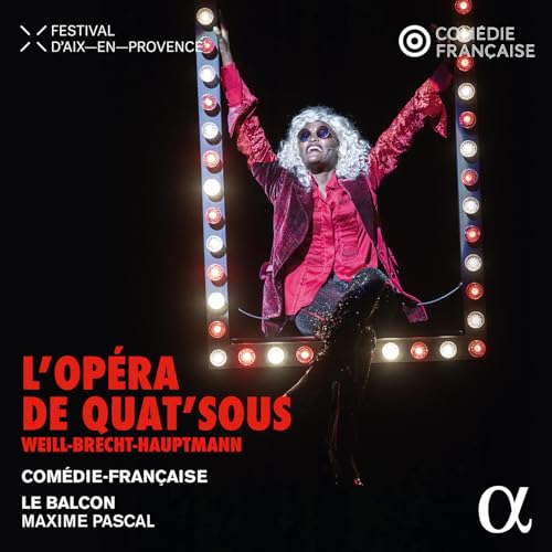 Performer in red suit poses within a bright, lit stage frame.