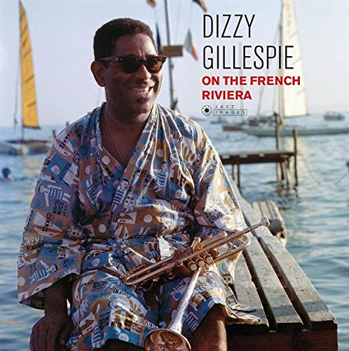 Dizzy Gillespie with trumpet, wearing patterned robe, by the sea.