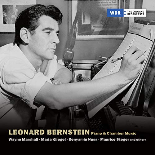 Black and white photo of Leonard Bernstein conducting at a piano.