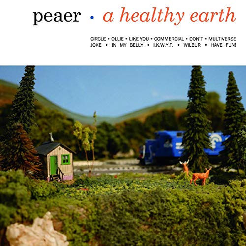 CD cover with miniature forest scene, cabin, train, and deer.