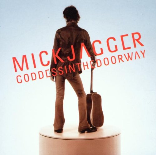 Mick Jagger standing with a guitar on a white cylindrical pedestal.
