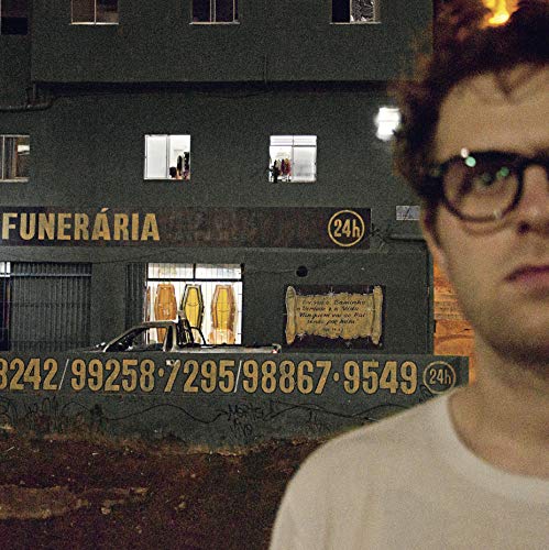 Man with glasses beside a building with a funeral home sign.