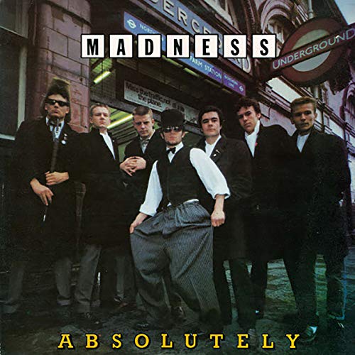 Madness band in suits pose near a London Underground entrance.