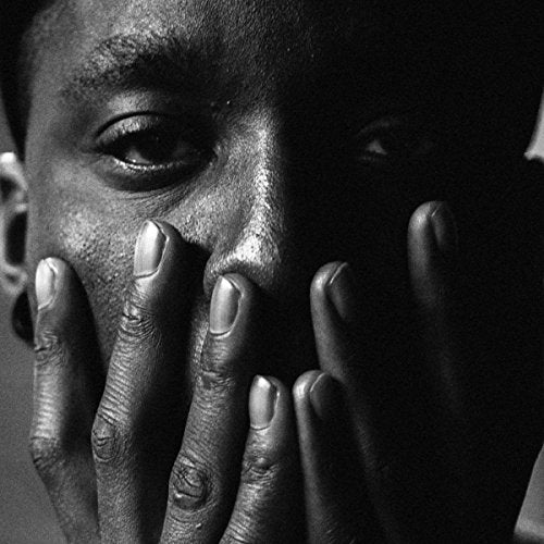 Black and white close-up of a person with hands covering their mouth.