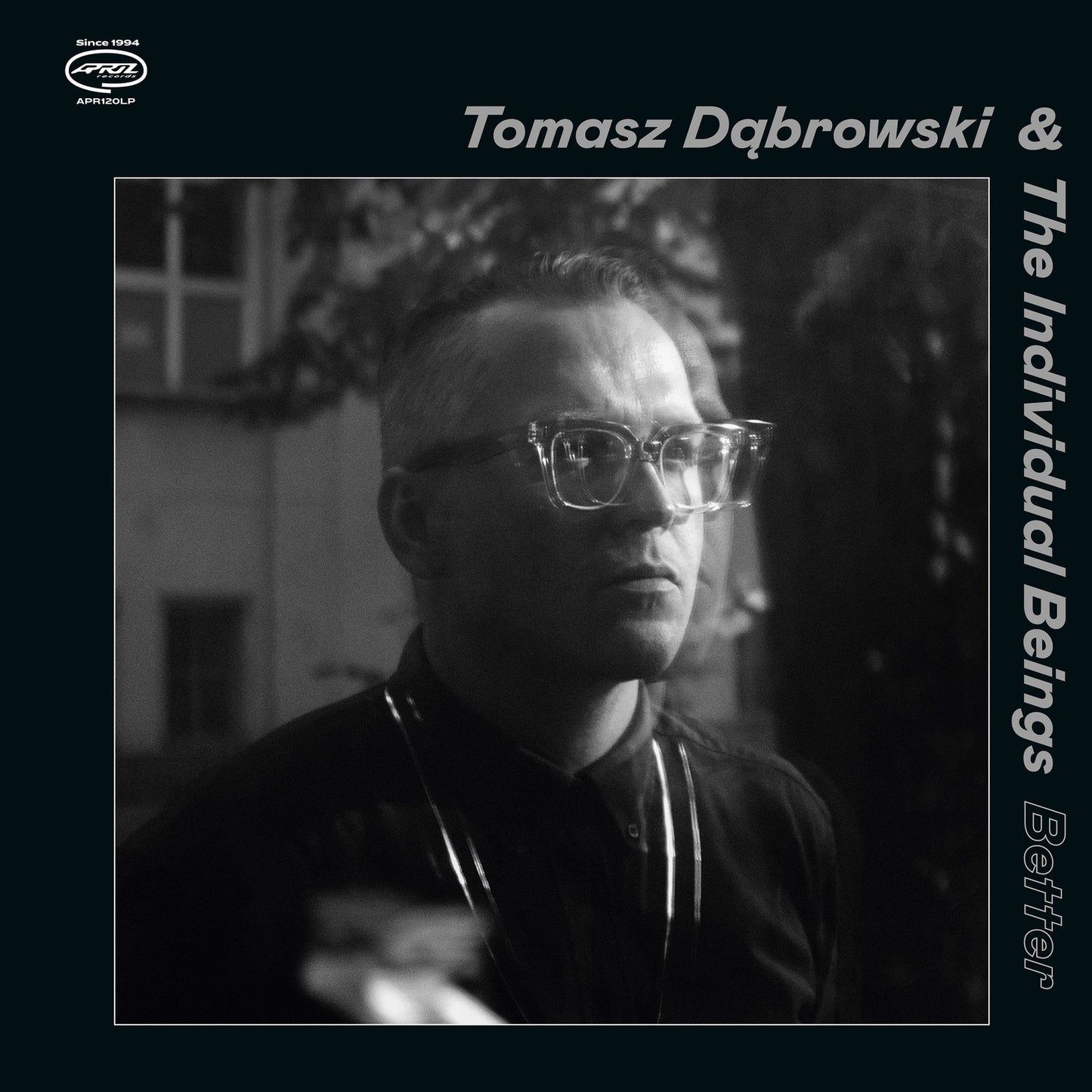Square album cover featuring a black and white portrait of a man with glasses.