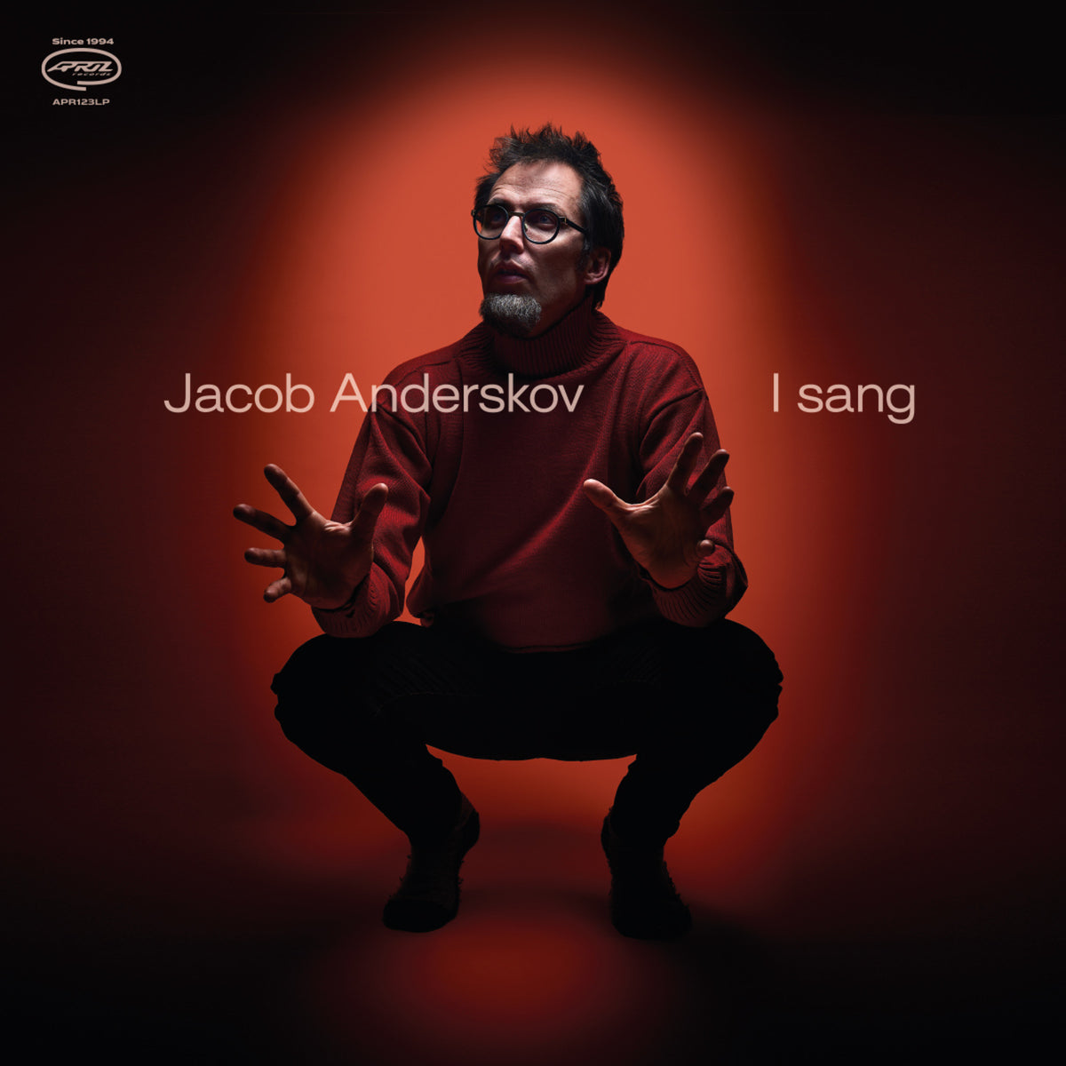 Jacob Anderskov album cover: man squatting with outstretched hands, red background.