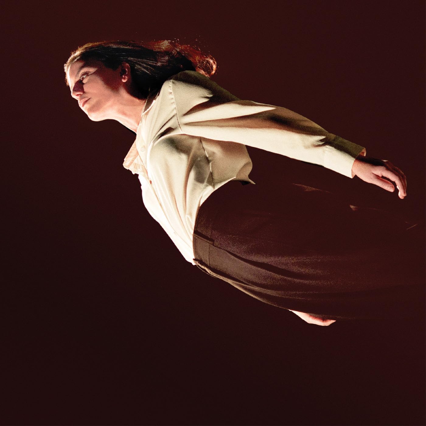 Woman in cream shirt appears to float against a dark red background.
