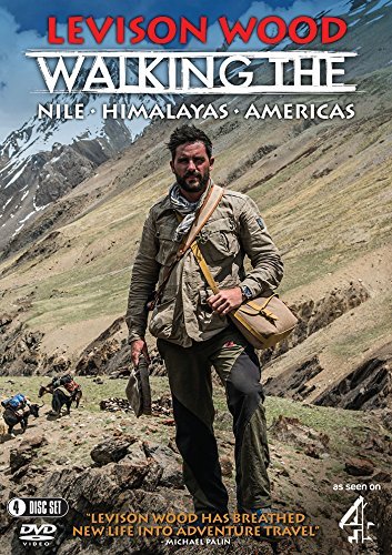 Levison Wood standing on a rocky mountain path with a satchel and pack animals.