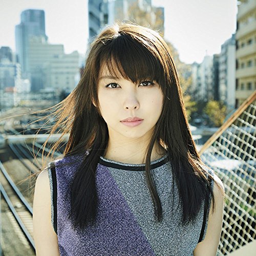 Young woman with long dark hair, city skyline in background.