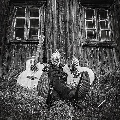Black and white photo of a person with guitars outdoors.