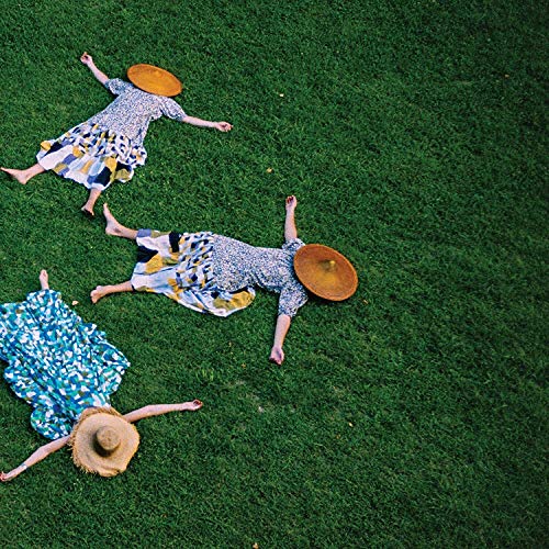 Three people lying in grass wearing patterned clothes and straw hats.
