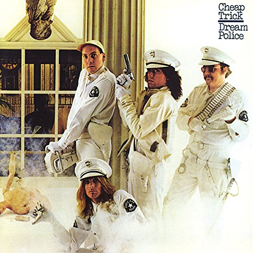 Four men in white police uniforms posing in a room with a large window.