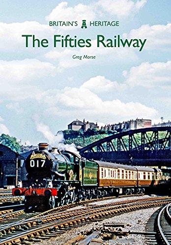 Steam train on railway tracks with town and bridge in background.