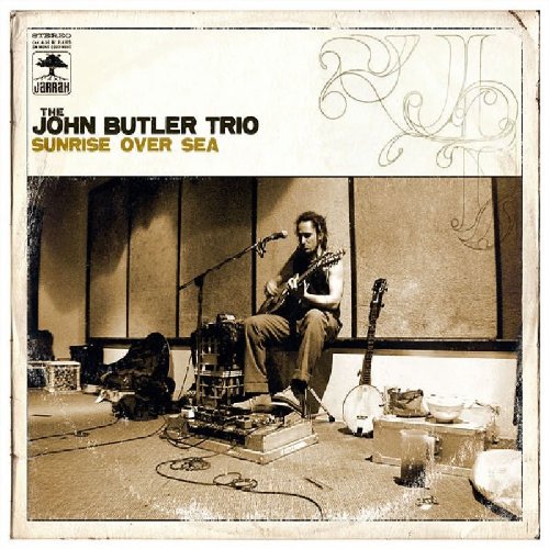 CD cover: musician with guitar seated in a cluttered room.