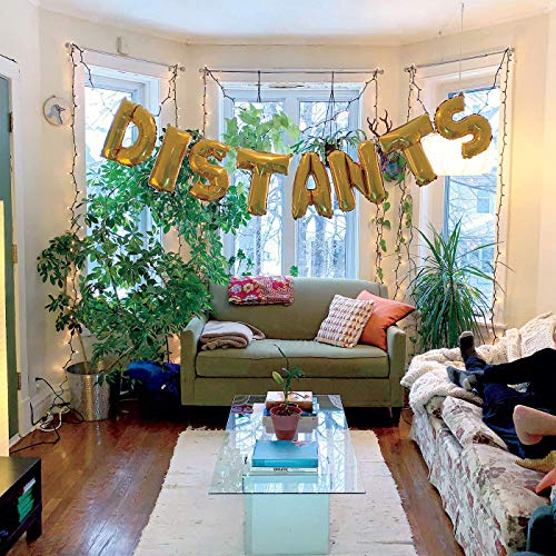 Living room with gold foil “DISTANTS” letters hanging above a green sofa.