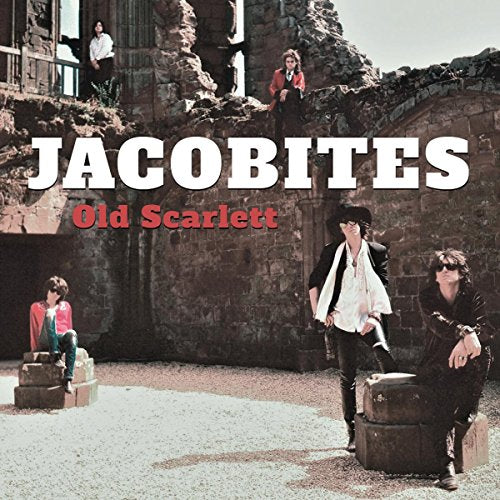 Five people posing in and around a ruined stone building with rubble on ground.