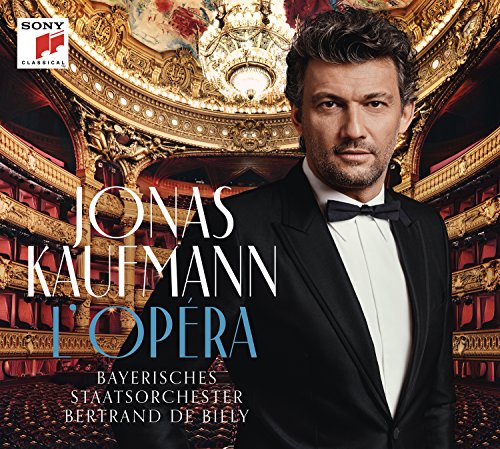 Jonas Kaufmann portrait in a tuxedo, standing in an ornate opera house.