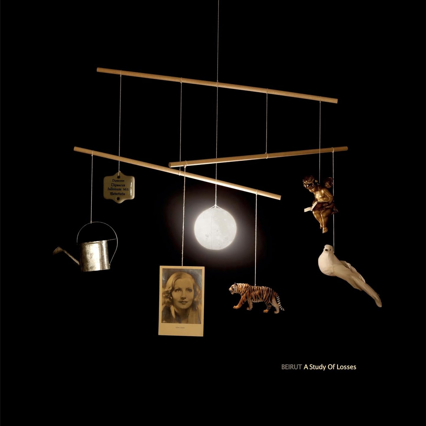 CD cover: hanging mobile with miniature objects against black background.