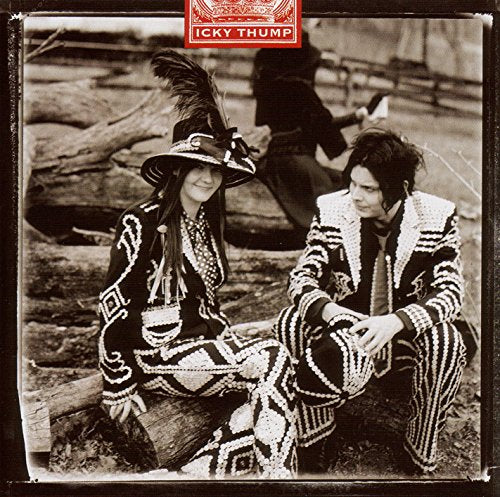Meg and Jack White wearing ornate patterned suits, sitting outdoors in a sepia photograph.